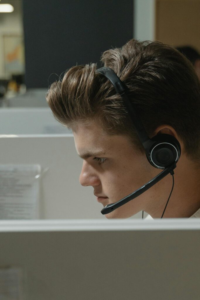 Close-up of a focused male call center agent wearing a black headset at work.